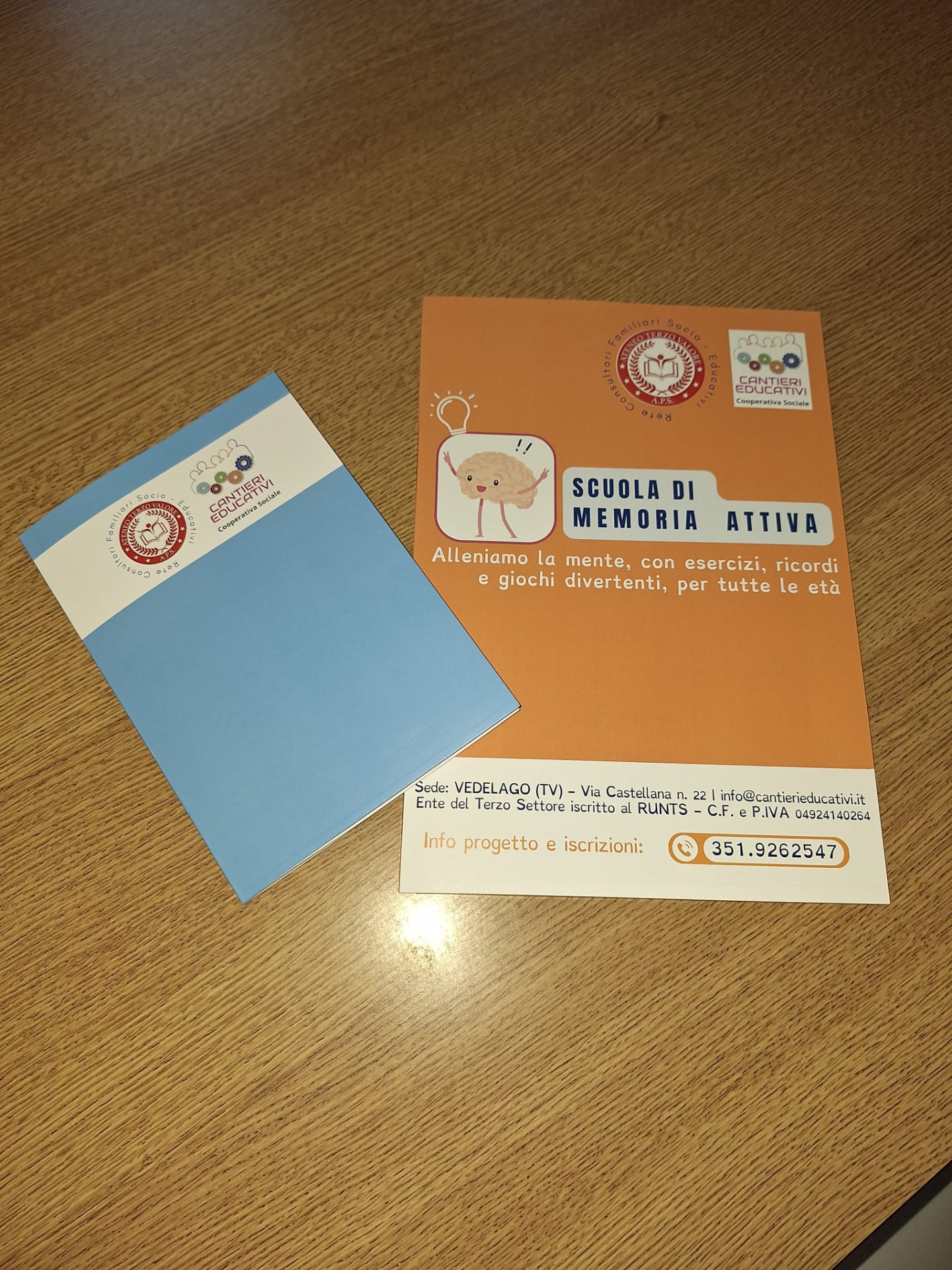 Quaderni degli esercizi e volantino della Scuola di Memoria Attiva® su un tavolo
